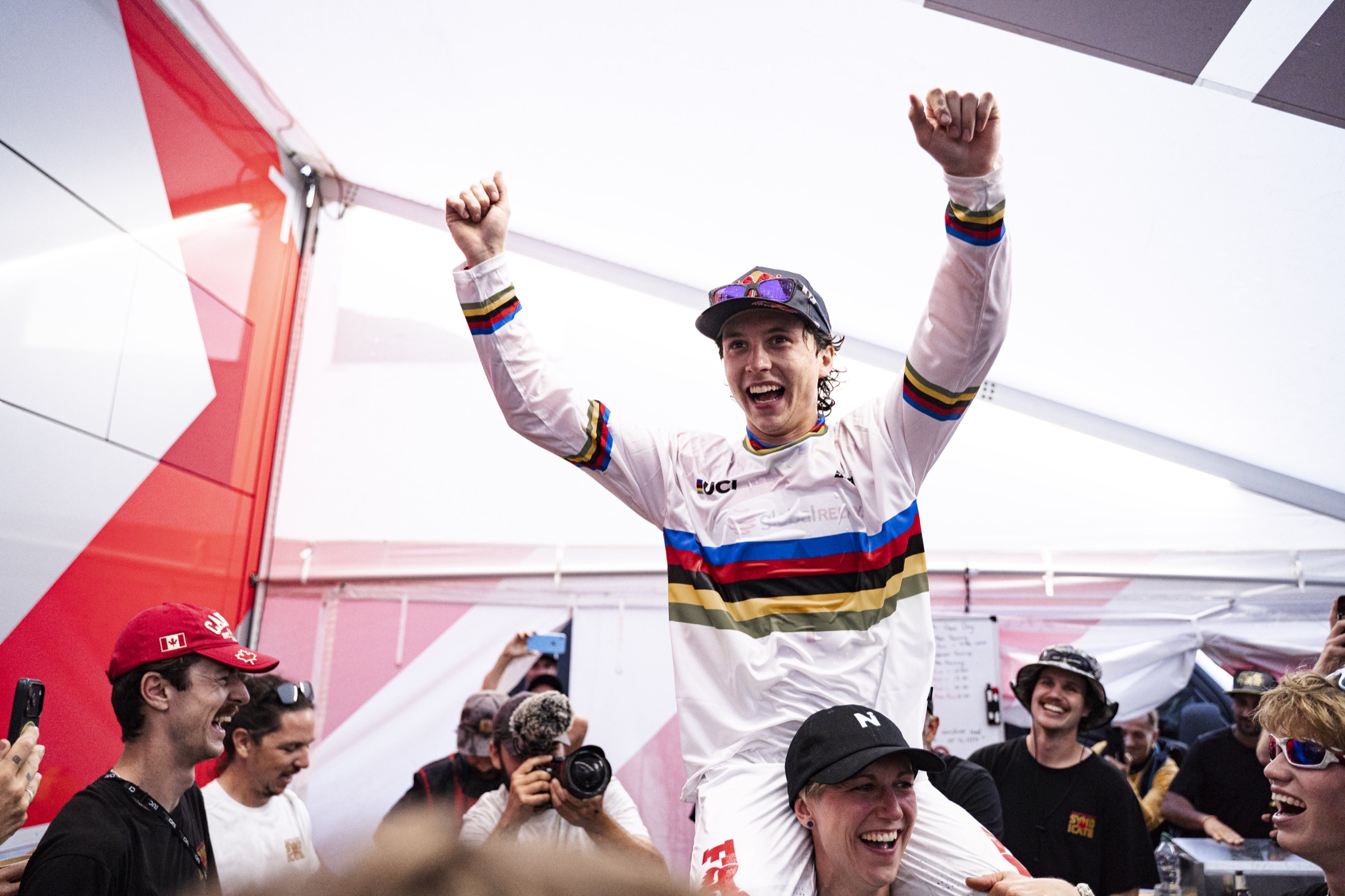 Downhill mountain biker mid-jump under the Red Bull arch at the World Championships